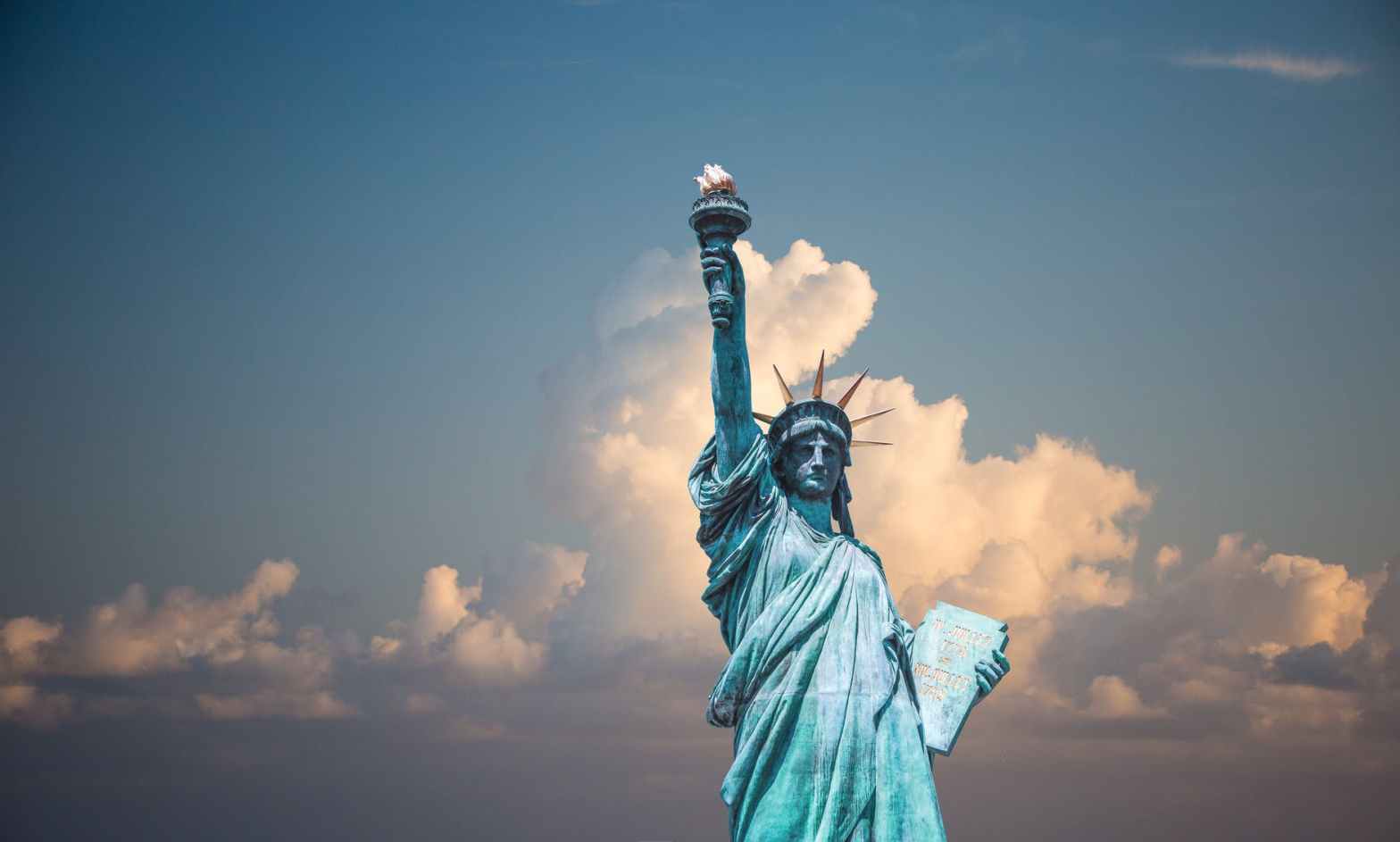 The Statue of Liberty standing tall against a backdrop of clouds and blue sky, symbolizing freedom, civic values, and the foundational role of public education in democracy.